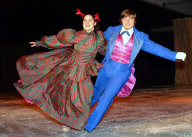 A waltzing couple linked by arms.  The woman has one foot out to the side.  Both skaters have their outside arms extended