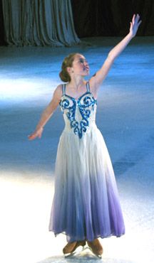 One skater dressed as an ice crystal posing with her arm above her head