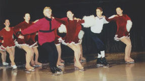 Carolers skate in a line, with four peoplein each row, linked by outstretched arms