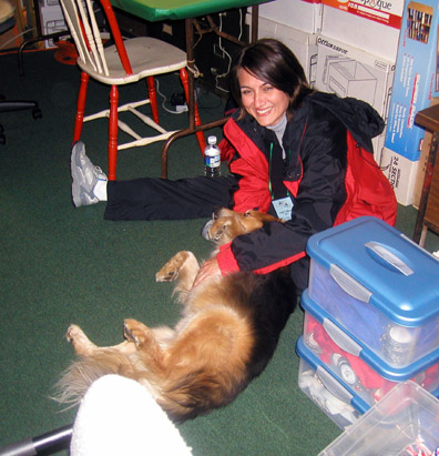 Angie sitting on the floor, playing with Ben, the dog.  Ben is laying on his back and Angie is petting him. 