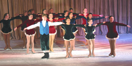 Three lines of skaters dressed as carolers with their arms oustretched and touching each other's shoulder