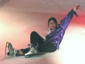 A jester sitting down on the ice posed with her arm above her head